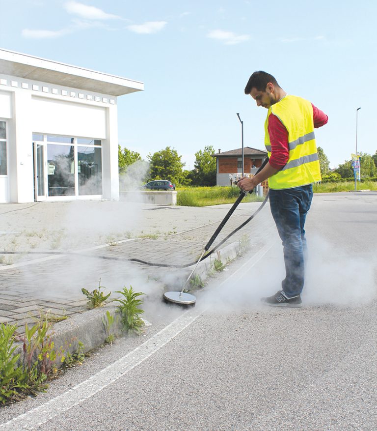 Commercial steam weed cleaner being used on a roadside, showcasing effective and eco-friendly weed control. This method ensures thorough weed removal without chemicals, suitable for maintaining cleanliness in public and commercial spaces.