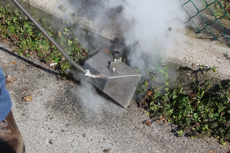 Steam weed removal system in use, demonstrating effective and eco-friendly weed control on a roadside. This system ensures thorough weed elimination without chemicals, suitable for maintaining cleanliness and safety in public and commercial areas.