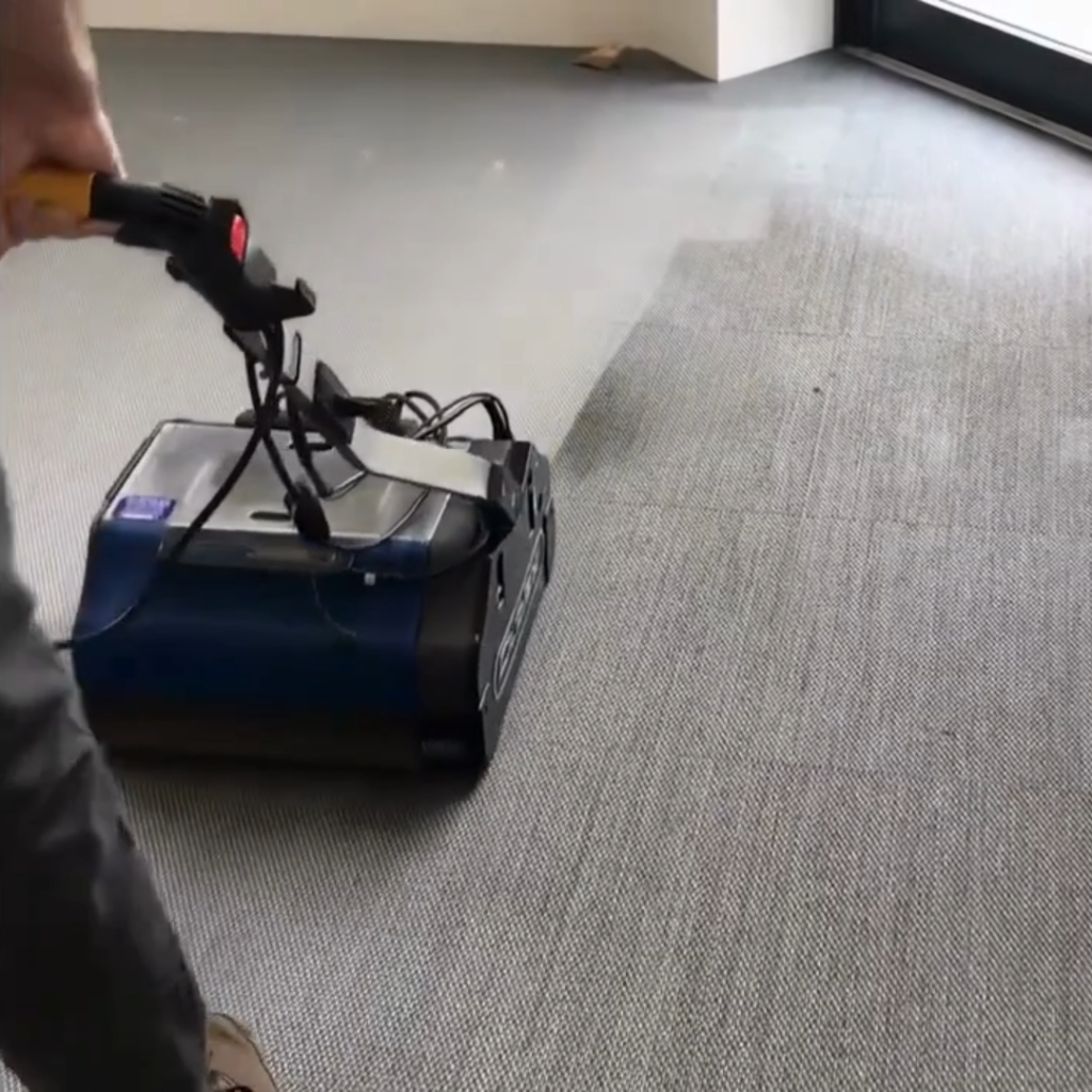 Duplex 420 floor machine cleaning grey carpet flooring in a commercial interior space