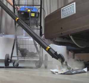 Jetsteam Maxi commercial steam cleaner connected with a steam mop, cleaning a healthcare facility floor with visible steam and medical equipment in the background.