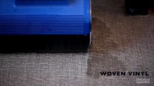 Duplex floor cleaning machine scrubbing a woven vinyl surface, showing a clear difference between cleaned and dirty areas