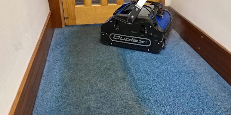 Commercial floor scrubber cleaning low pile carpet in a narrow corridor